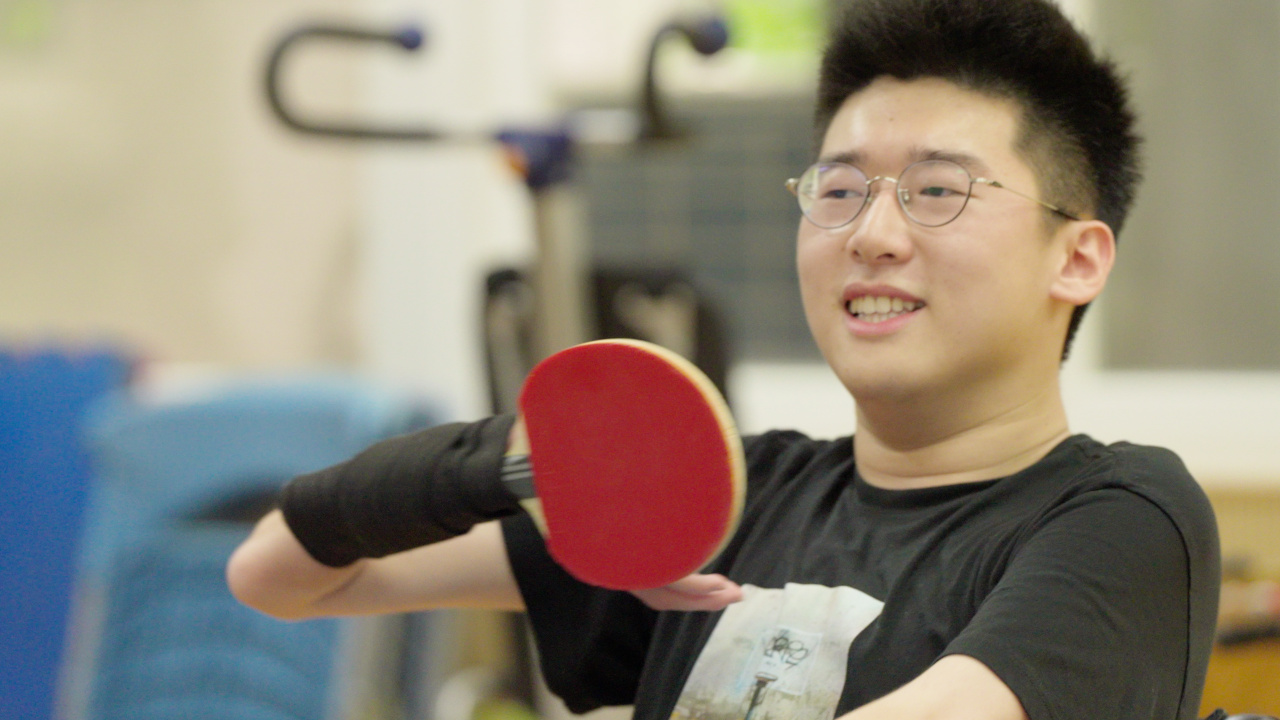 文凱用彈性纏著球拍打乒乓球